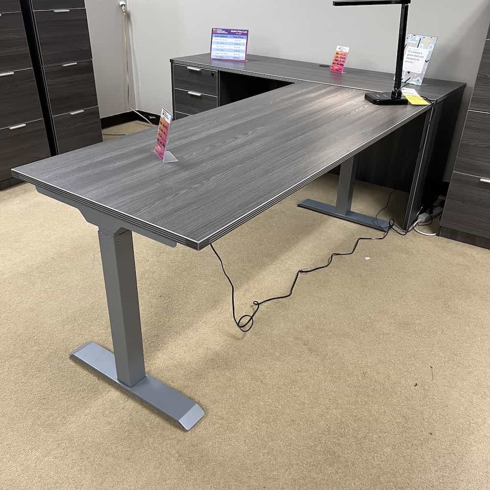 height adjustable desk making an L shape next to a credenza desk with one 3 drawer file cabinet, grey, front view