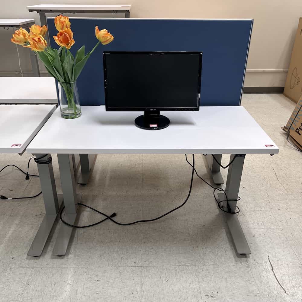 white adjustable height desk with black monitor and yellow flowers