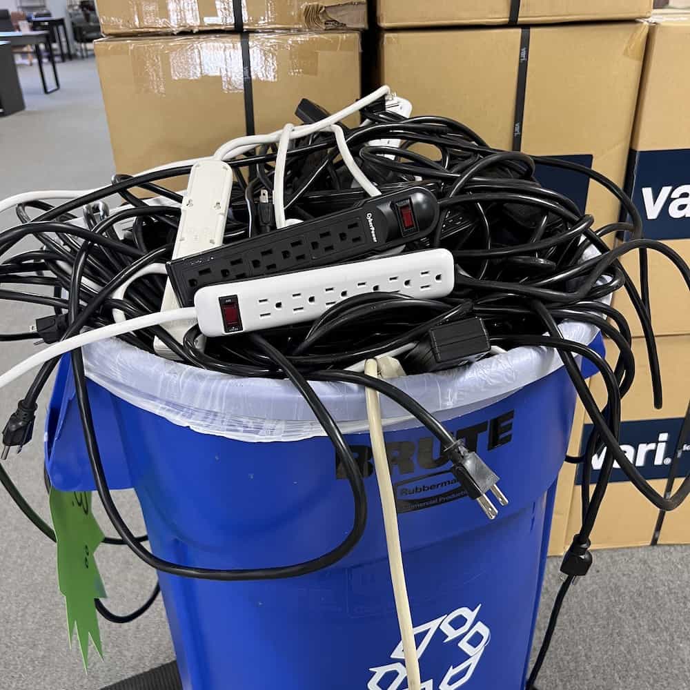recycle bin can full of serge protector cords, white and black