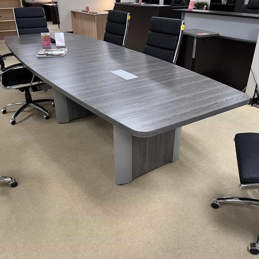 grey boat shaped conference table with elliptical base, some chairs around table