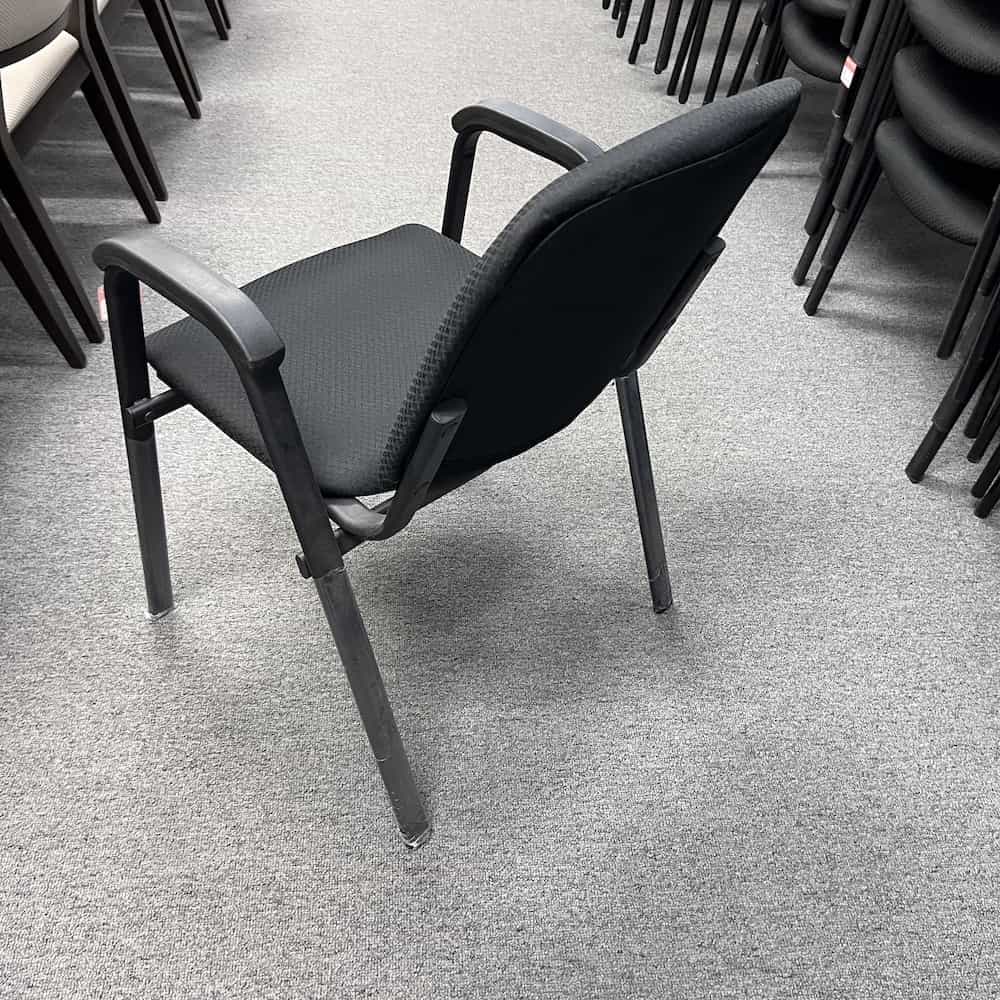 black upholstered stacking chair with arm rests