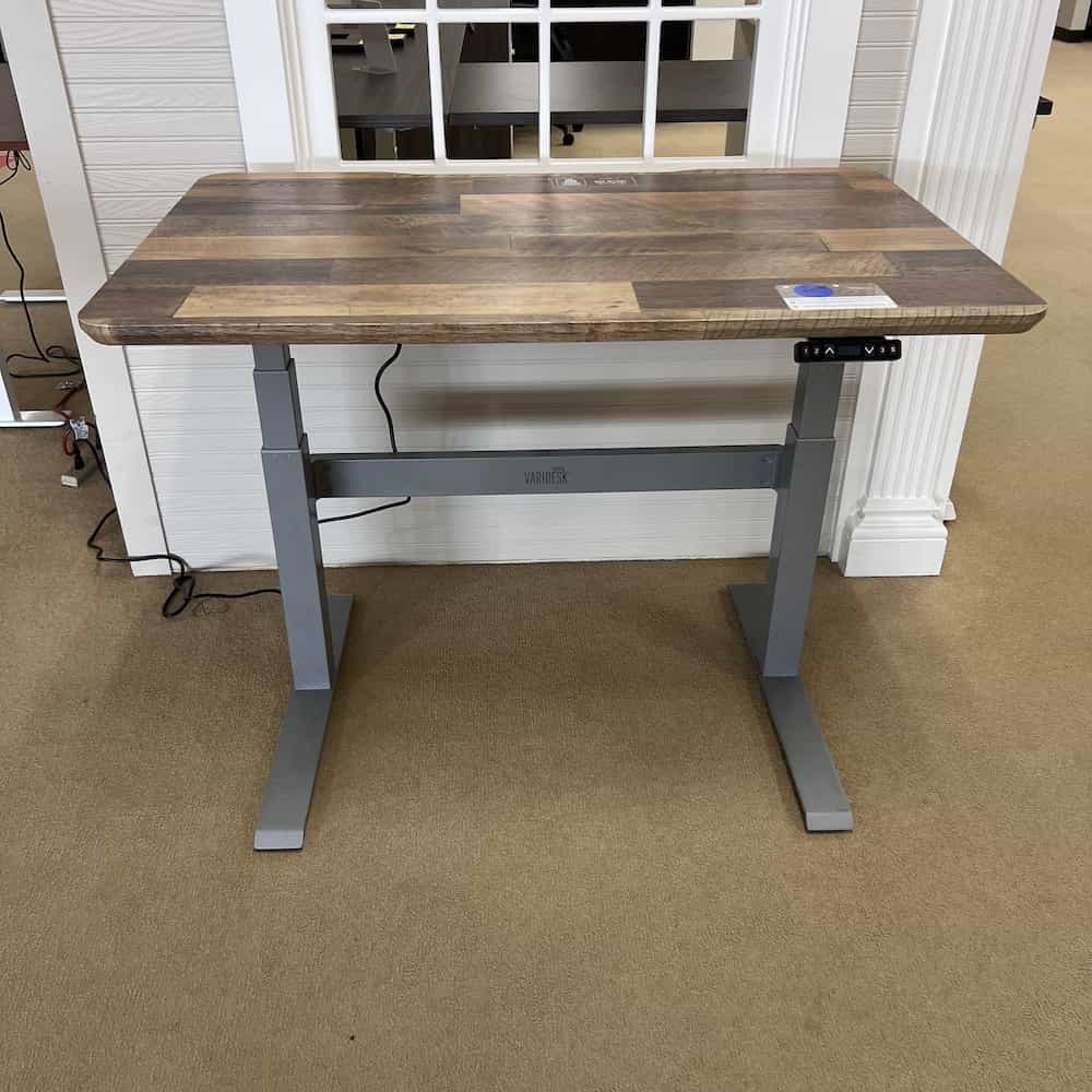 a woodgrain laminate vari desk top with a grey metal base