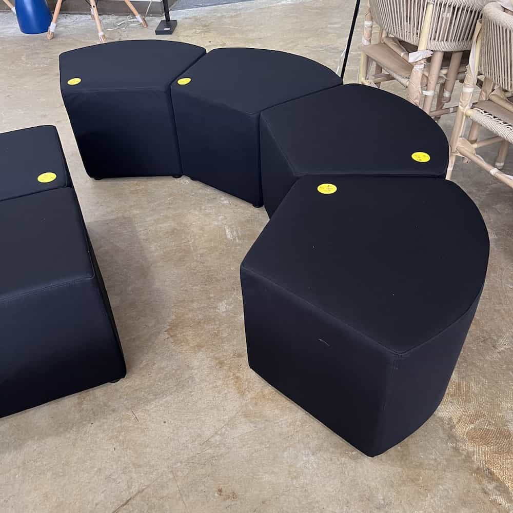 black upholstered ottomans arranged in a curve