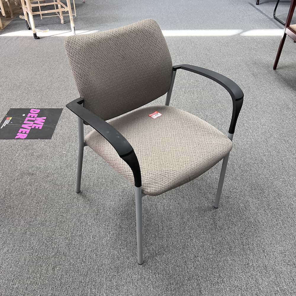 Beige stacking chair with black arm rests