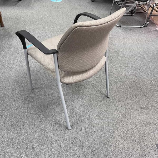 Beige stacking chair with black arm rests