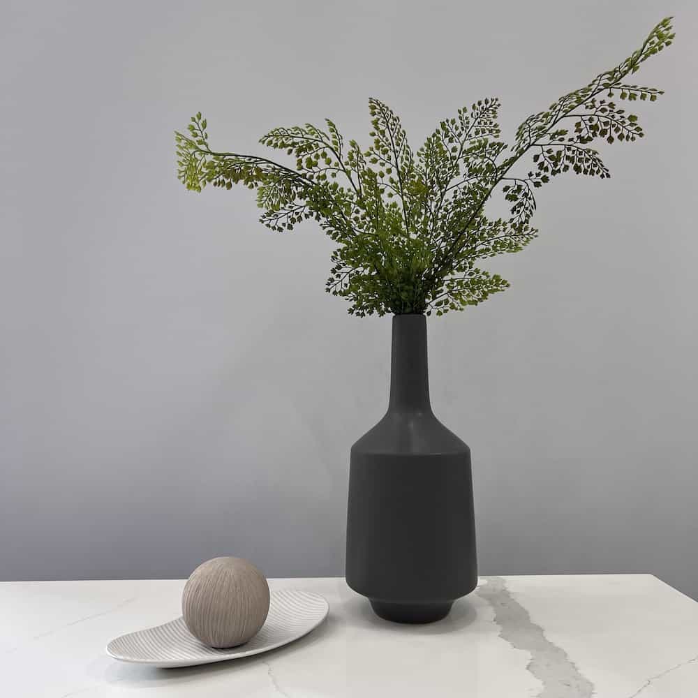decor: grey tall vase with faux greenery, white oval plate, taupe grey ceramic ball