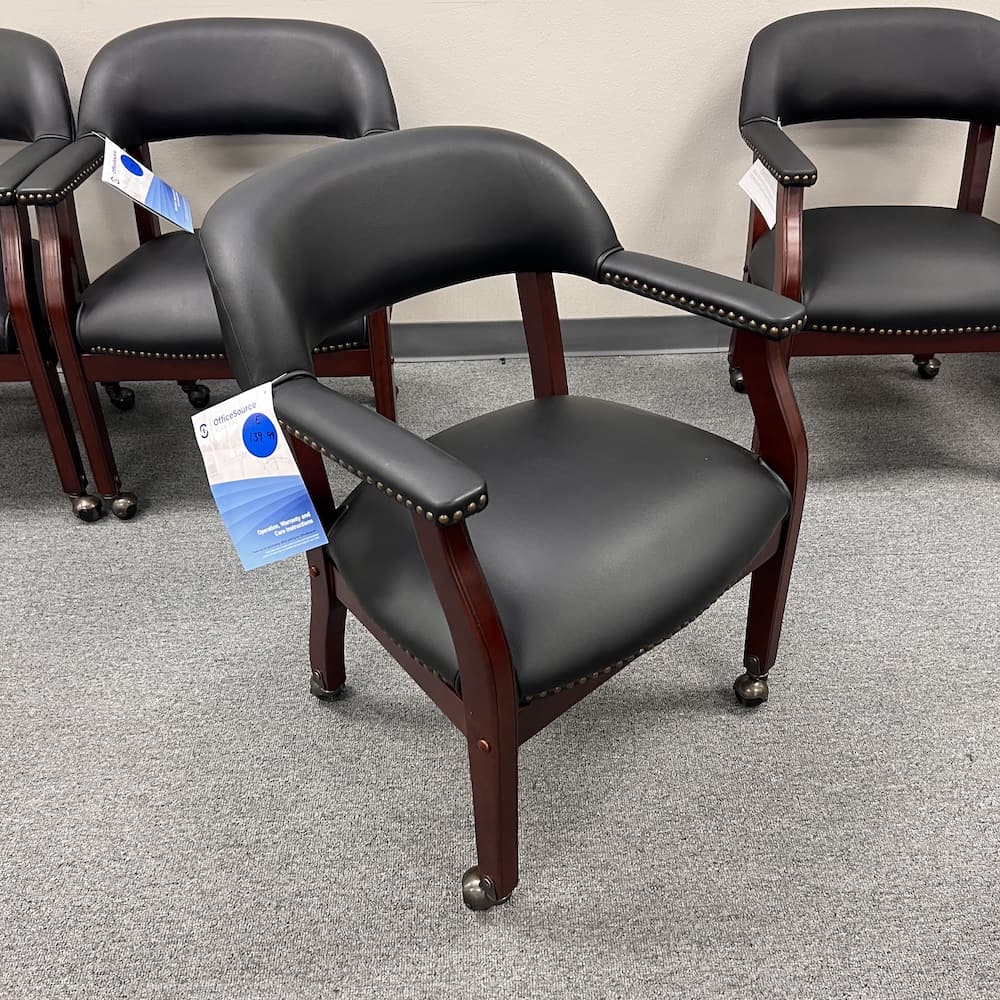 black vinyl poker guest chair with mahogany veneer wood, brass studs, and brass wheels. Office furniture seating