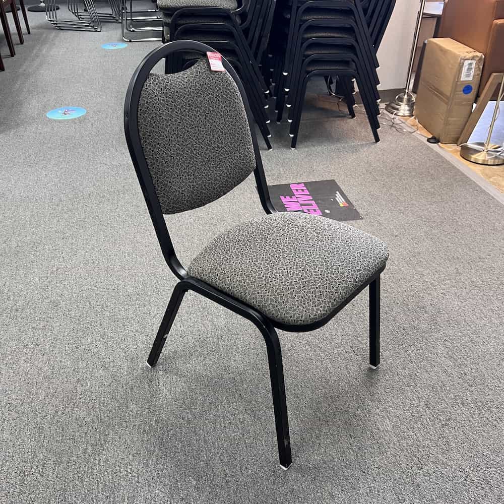 grey upholstered stacking chair with black metal base and legs