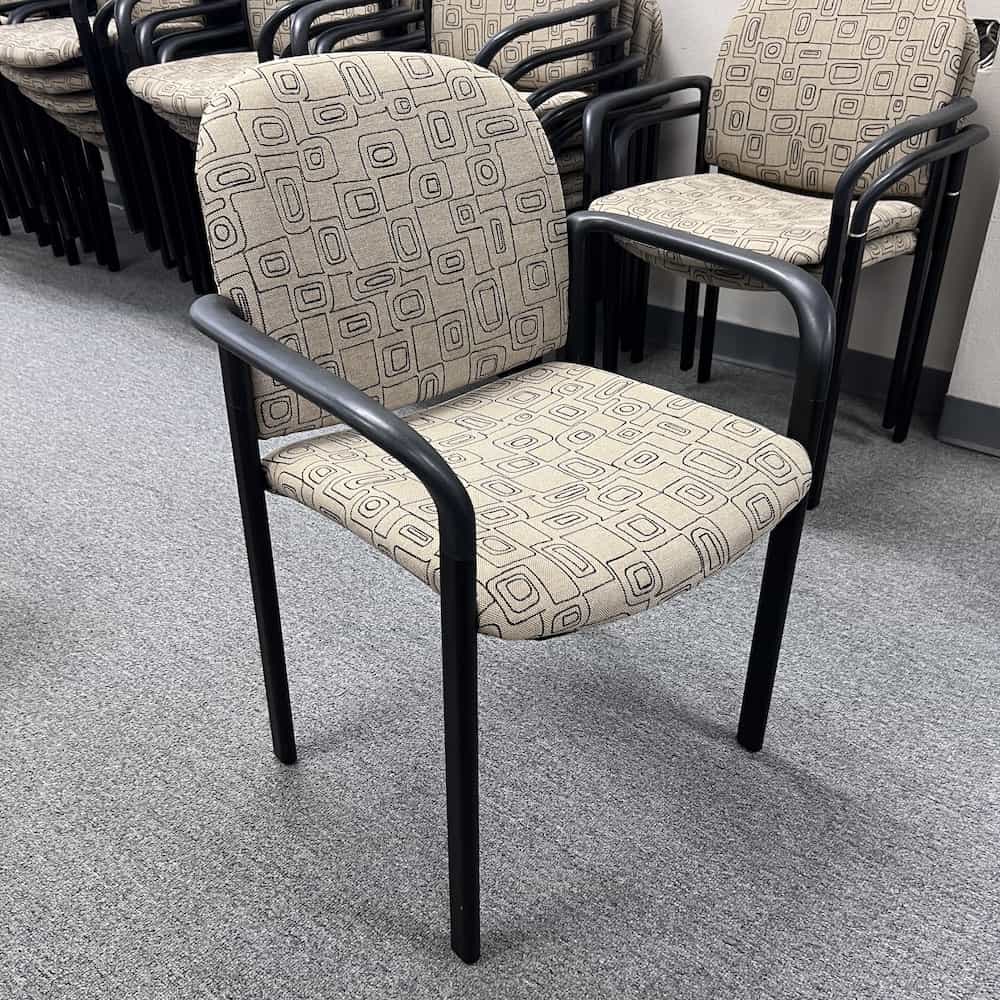 tan with organic outlined shapes on upholstered seat, black arms and legs, stacking chair