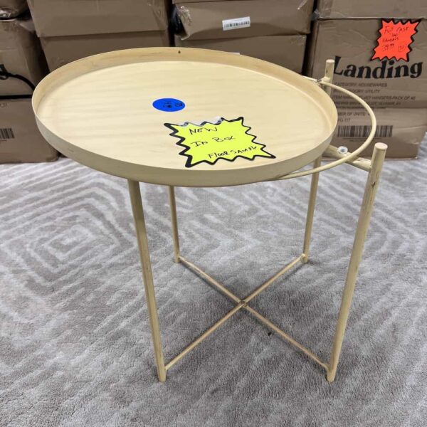tan yellow metal table, small, x base and four legs, top slightly askew