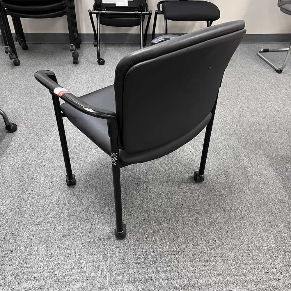 hon brand black vinyl stacking chair with arms, rolling, back view