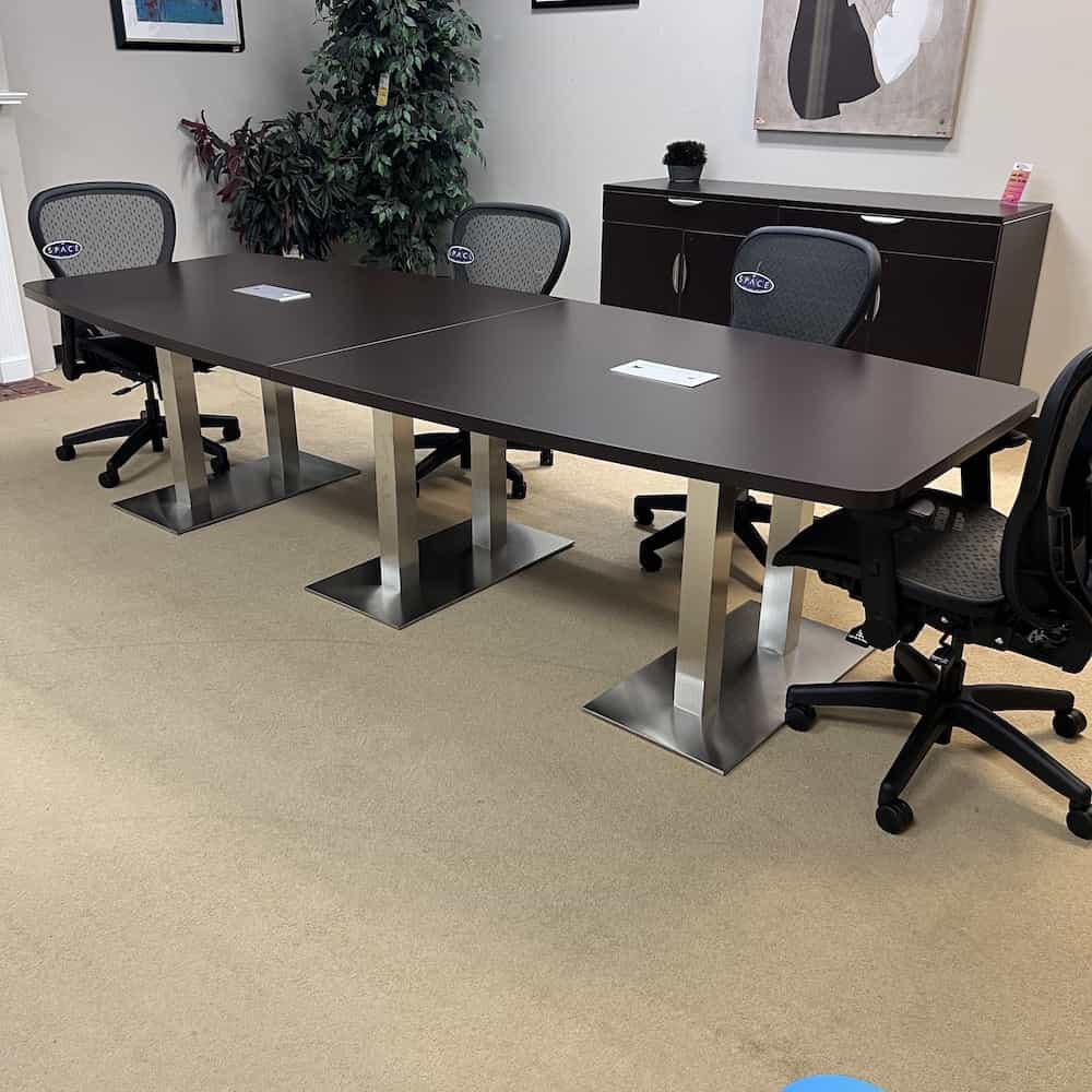 boat shaped conference table with silver legs attached to a silver base