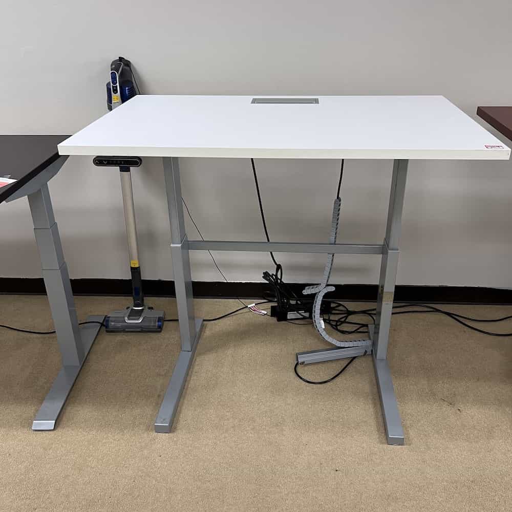 white topped standing desk with silver legs, teknion, with a silver cord management