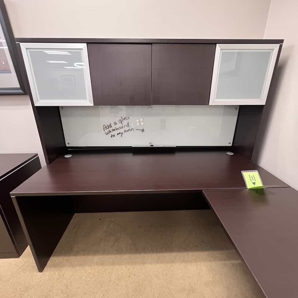 glass dry erase white board mounted on a hutch on a desk, underneath the cabinets