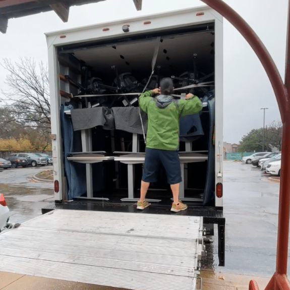 image of man in green jacket loading desks onto a moving truck