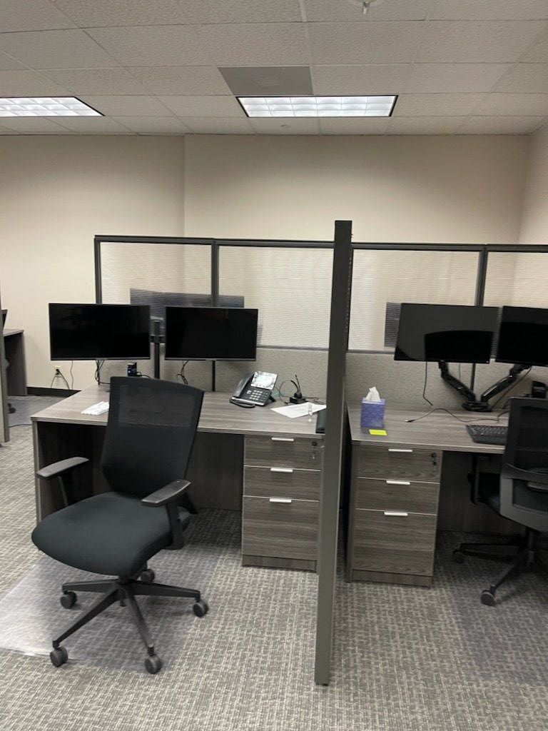 a photo showing brand new office furniture just installed, grey desks with paneling, monitor arms
