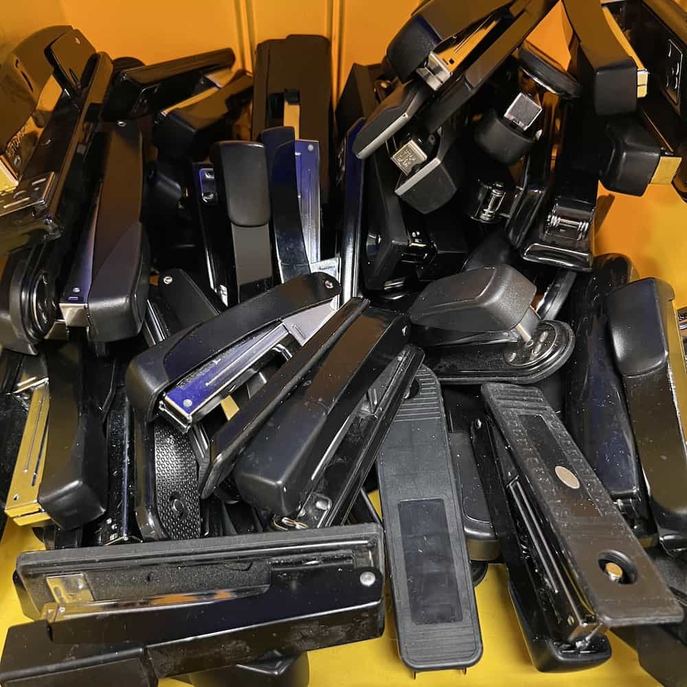 pile of black metal staplers office used