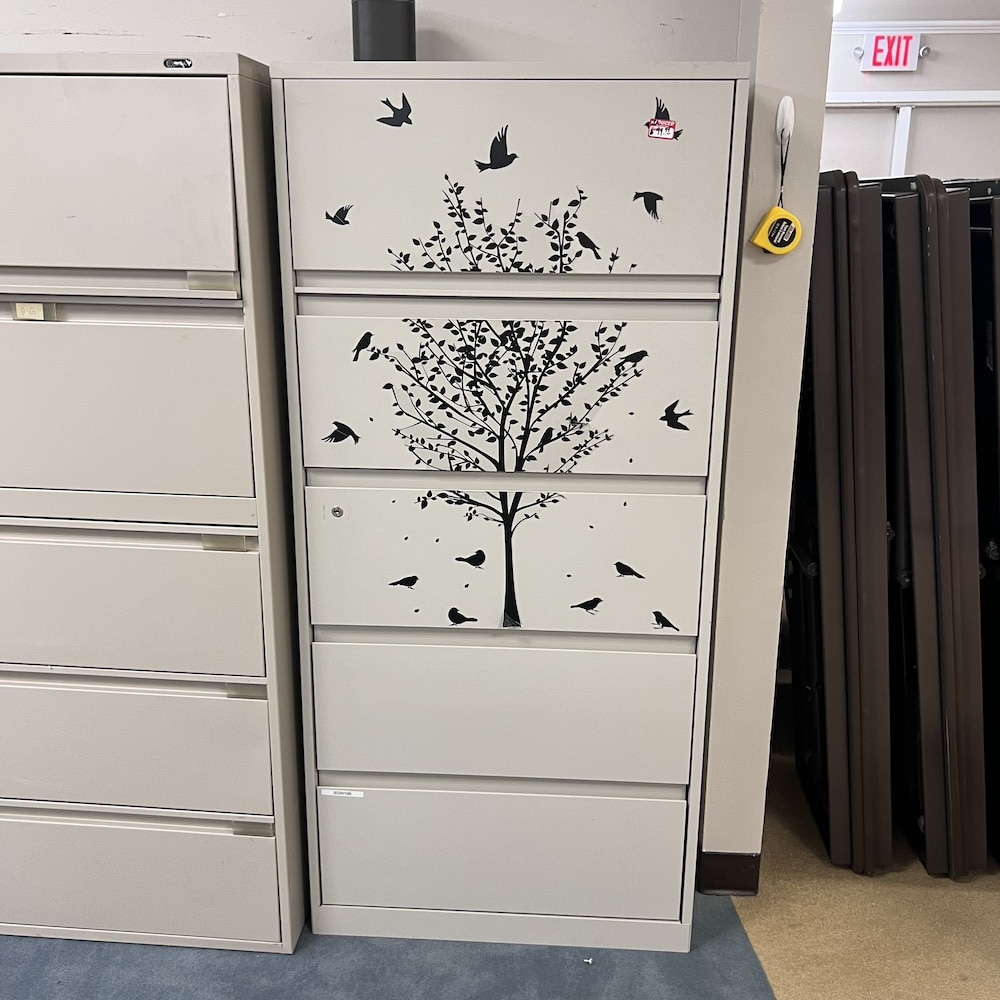 a beige metal 5 drawer lateral with a tree and bird sticker on the front used steelcase metal