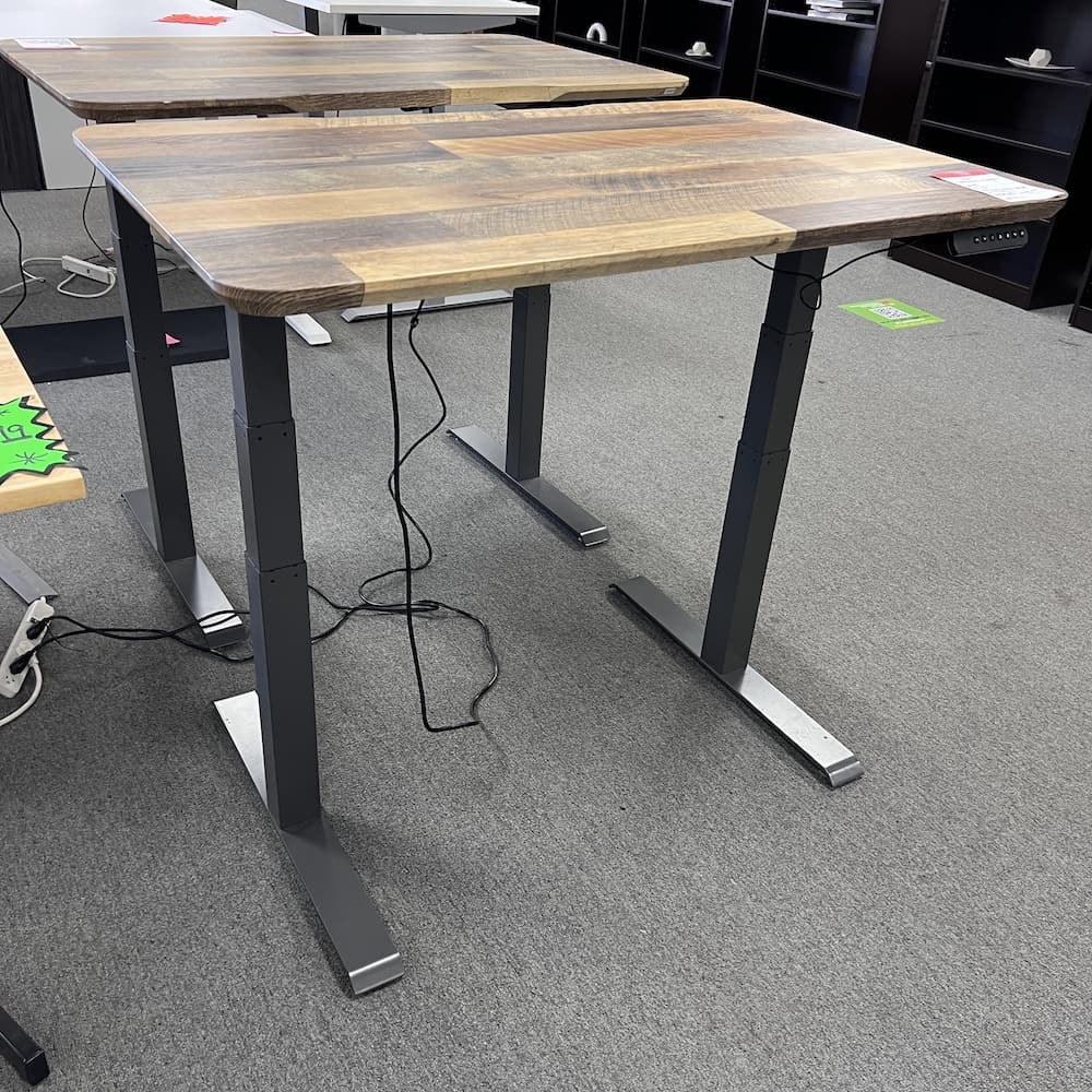a woodgrain laminate vari desk top with a grey metal base, used office furniture, standing desk