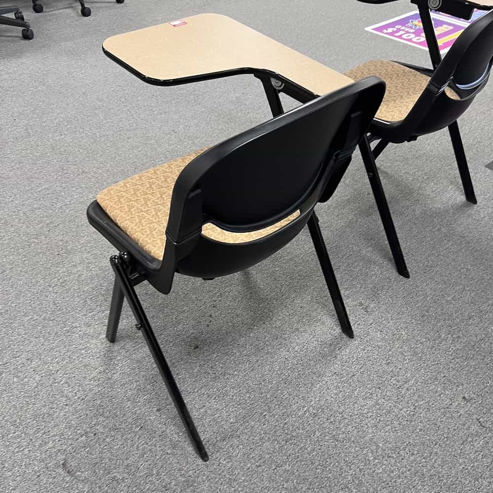 tan laminte table with black plastic seat with tan upholstered seat. School chair with retracting table