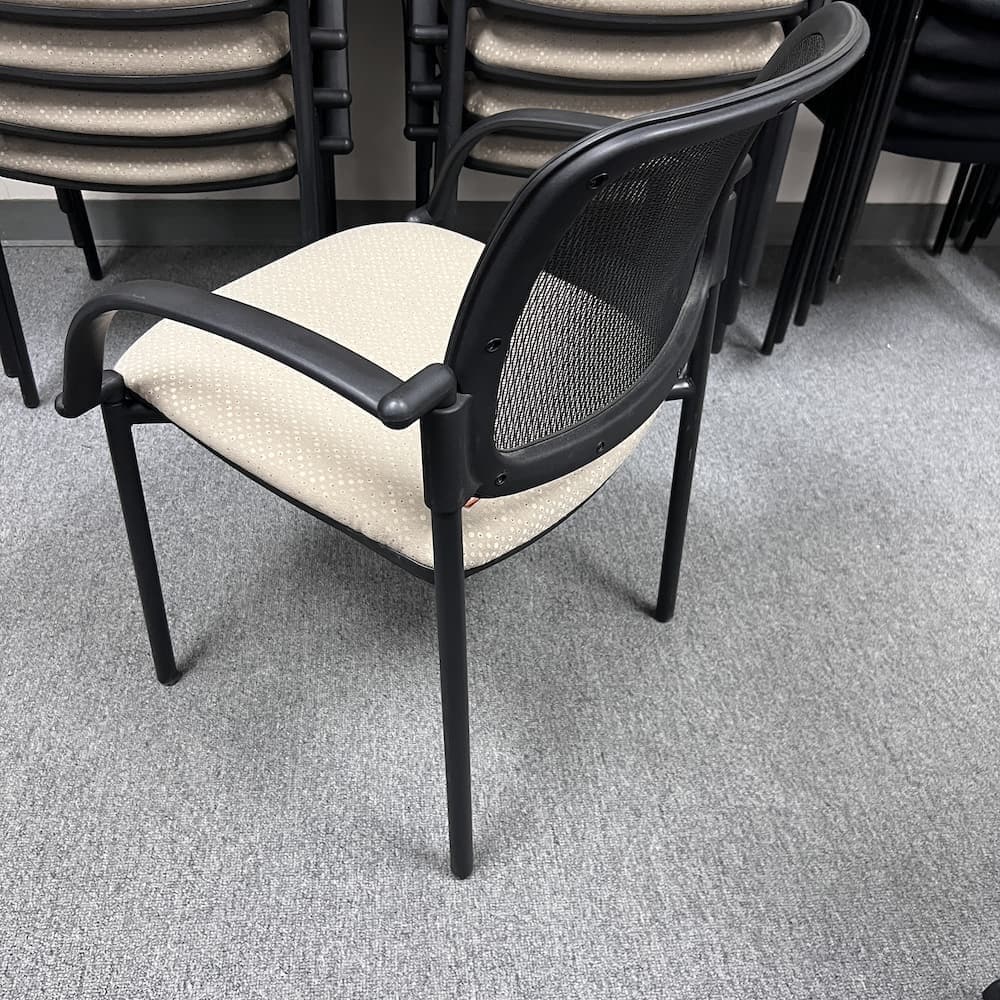 beige upholstered stacking chair with black mesh back