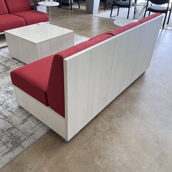 red sofa with white wood washed laminate base with cubbies and board back corporate office lounge reception area with side table set used office furniture