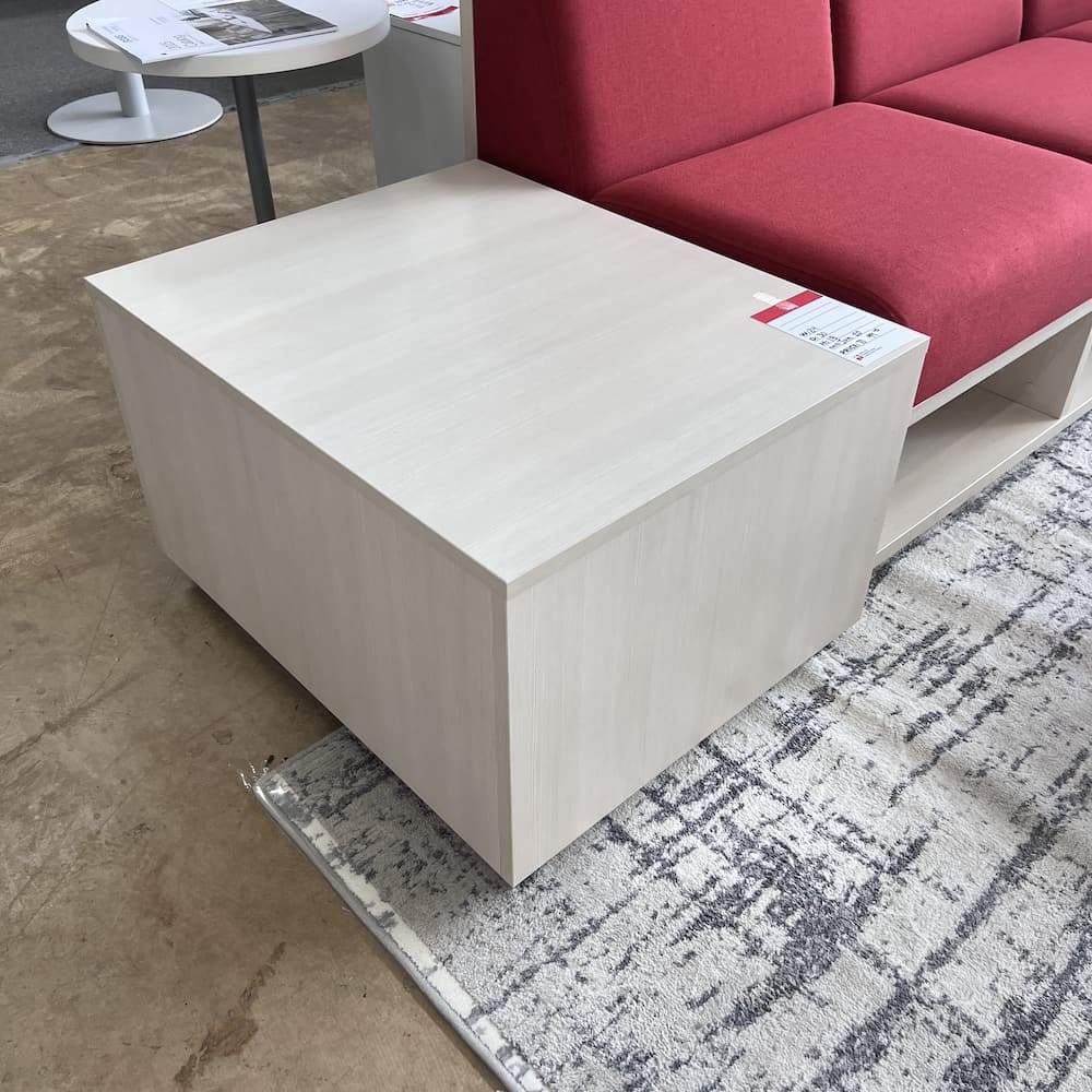 red sofa with white wood washed laminate base with cubbies and board back corporate office lounge reception area with side table set used office furniture