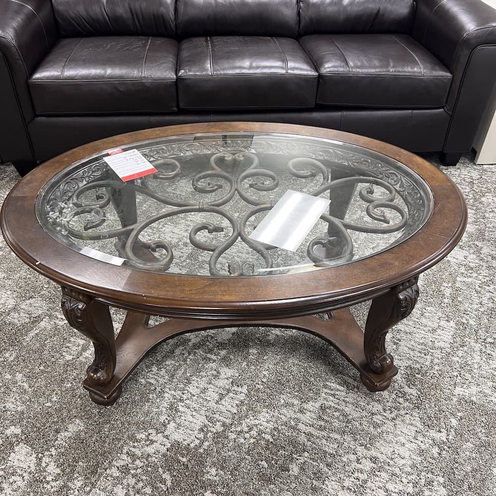 Ashley nor castle coffee table, oval with glass and iron detail swirls, used furniture