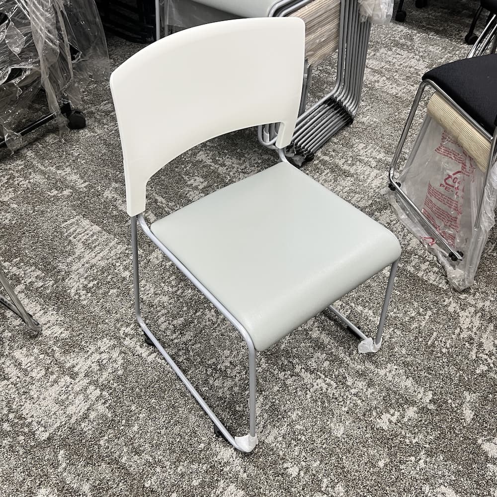 white stacking chair with light blue vinyl padded seat and silver legs, used office furniture