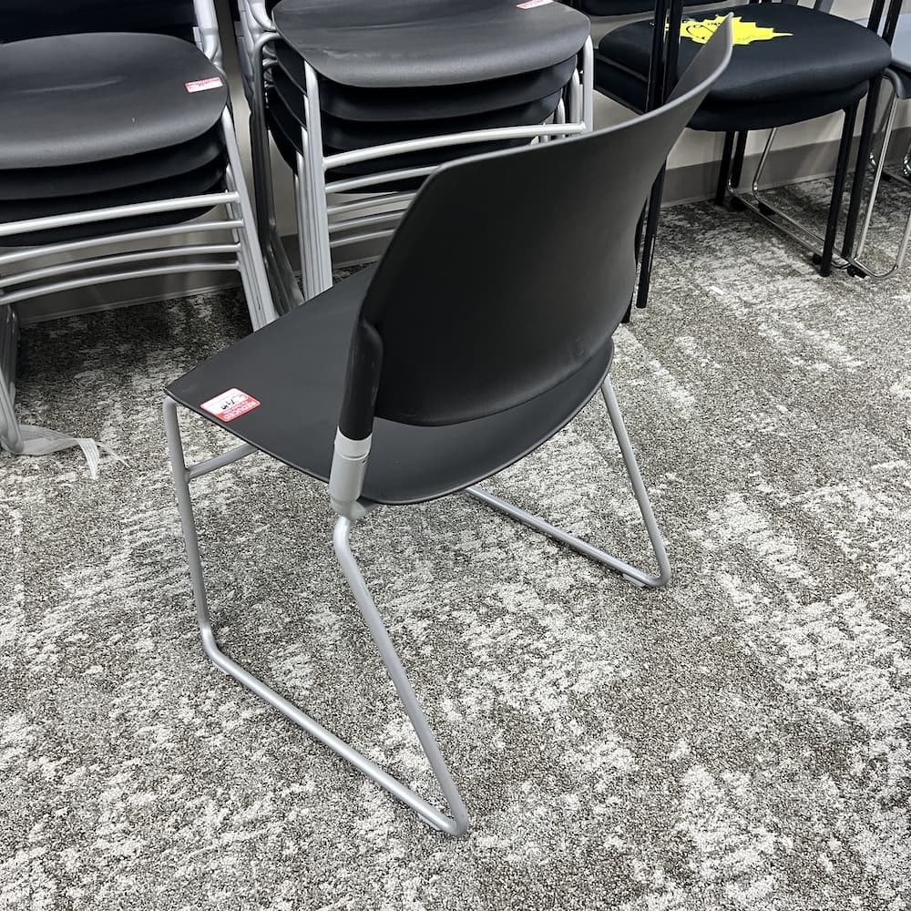 black plastic stacking chair with black arms and chrome base, open box office furniture